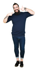 Young hipster man with long hair and beard wearing glasses smiling confident showing and pointing with fingers teeth and mouth. Health concept.