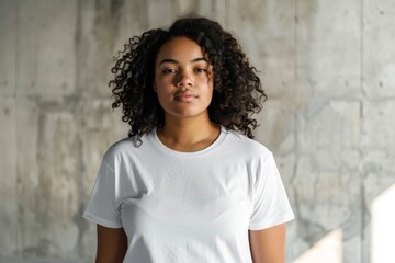 A confident plus size African American woman wearing a crisp white t-shirt stands in a studio setting against a neutral background