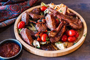 Grilled meats and fresh vegetables on wooden platter