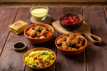 chicken in spices and vegetables stewed on the table next to sesame seeds and soy sauce