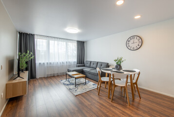 Fototapeta premium Modern Home Living Room Interior. Luxurious Stylish Modern Apartment. Open Interior, Stylish Sofa, Coffee Table, Scandinavian Design. TV Screen, Windows and Curtains.