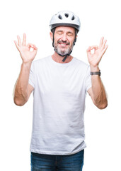 Naklejka premium Middle age senior hoary cyclist man wearing bike safety helment isolated background relax and smiling with eyes closed doing meditation gesture with fingers. Yoga concept.