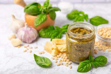 Pesto. Italian basil pesto sauce on a textured wooden background. Ingredient for pesto sauce: fresh basil, pine nuts, Parmesan cheese and olive oil. Space for text.Copy space.