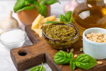 Pesto. Italian basil pesto sauce on a textured wooden background. Ingredient for pesto sauce: fresh basil, pine nuts, Parmesan cheese and olive oil. Space for text.Copy space.