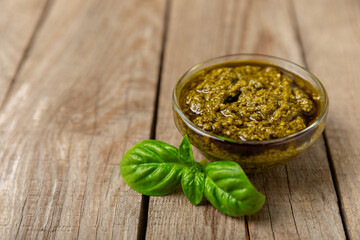 Pesto. Italian basil pesto sauce on a textured wooden background. Ingredient for pesto sauce: fresh basil, pine nuts, Parmesan cheese and olive oil. Space for text.Copy space.