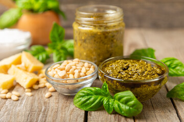 Pesto. Italian basil pesto sauce on a textured wooden background. Ingredient for pesto sauce: fresh basil, pine nuts, Parmesan cheese and olive oil. Space for text.Copy space.