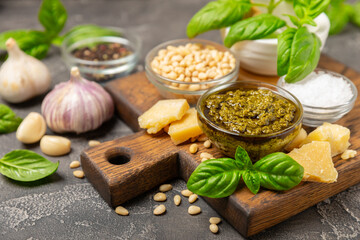 Pesto. Italian basil pesto sauce on a textured wooden background. Ingredient for pesto sauce: fresh basil, pine nuts, Parmesan cheese and olive oil. Space for text.Copy space.