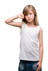Fototapeta premium Young blonde toddler with angry face, negative sign showing dislike with thumbs down, rejection concept