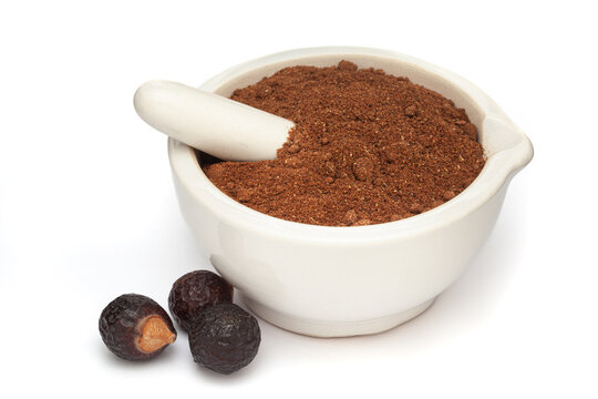 Close-up of Organic Soapnut or Reetha (Sapindus mukorossi) powder with its Fruits, in white ceramic mortar and pestle, isolated on a white background.