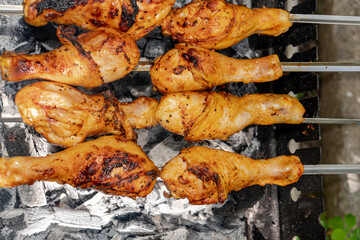 Chicken shanks on skewers on grill, grilling.