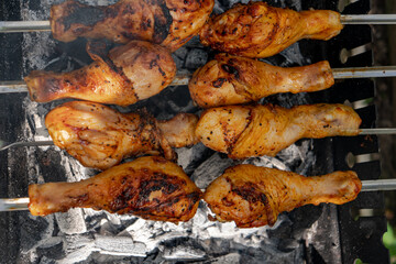 Chicken shanks on skewers on grill, grilling.