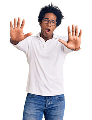 Naklejka premium Handsome african american man with afro hair wearing casual clothes and glasses doing stop gesture with hands palms, angry and frustration expression