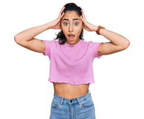 Hispanic teenager girl with dental braces wearing casual clothes crazy and scared with hands on head, afraid and surprised of shock with open mouth