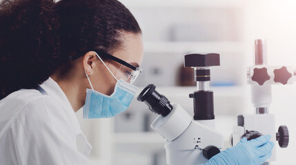 Microscope, woman and scientist research for disease study with face mask and safety gear, Virus, laboratory and medical work with bacteria check and investigation of monkey pox for science journal