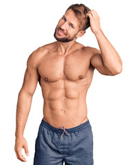 Fototapeta premium Young caucasian man standing shirtless confuse and wonder about question. uncertain with doubt, thinking with hand on head. pensive concept.