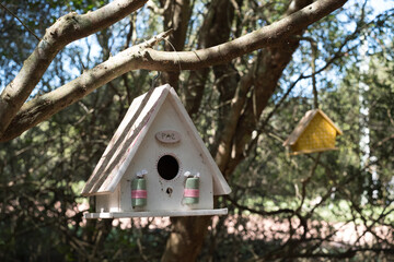 A white birdhouse with a pink ribbon hanging from it