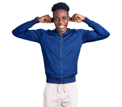 Young african american man wearing sportswear smiling pulling ears with fingers, funny gesture. audition problem