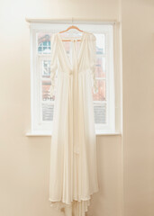 White Wedding Dress Hanging In Front Of Window