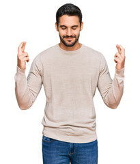 Fototapeta premium Young hispanic man wearing casual clothes gesturing finger crossed smiling with hope and eyes closed. luck and superstitious concept.
