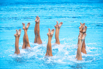 Artistic swimming team in swimming pool performing synchronized legs movement