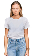 Fototapeta premium Beautiful young blonde woman wearing casual white t shirt relaxed with serious expression on face. simple and natural looking at the camera.