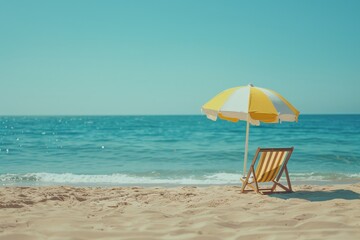 A sunny beach scene with a yellow and white umbrella shading a wooden chair positioned to face the tranquil ocean, everything under a clear blue sky inviting relaxation and peace.