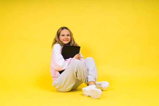 Teenager girl with notebok computer laptop sitting in studio