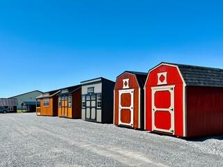 American style wooded sheds in a row. A shed is typically simple, single-story roofed structure in a back garden or on an allotment that is used for storage, hobbies, or as a workshop.