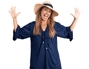 Middle age hispanic woman wearing summer hat showing and pointing up with fingers number ten while smiling confident and happy.