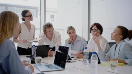 A group of young business people collaborate and brainstorm in a modern office, planning for success. The diverse employees engage in a productive session, focusing on teamwork and communication