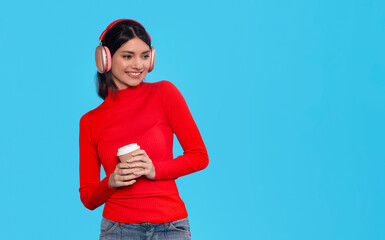 Young Woman Listening To Music While Holding Coffee Cup