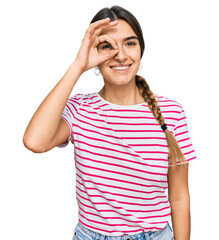 Young hispanic woman wearing casual clothes doing ok gesture with hand smiling, eye looking through fingers with happy face.