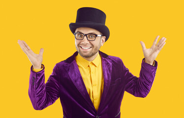 Entertainer presents new holiday circus show program. Man wearing purple velvet suit and tophat spreads hands, smiles and looks at camera with happy funny face expression isolated on yellow background
