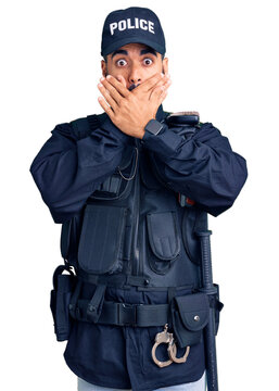 Young hispanic man wearing police uniform shocked covering mouth with hands for mistake. secret concept.