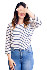 Fototapeta premium Beautiful young brunette woman wearing casual clothes and glasses smiling and laughing with hand on face covering eyes for surprise. blind concept.