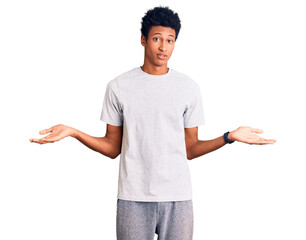 Young african american man wearing casual clothes clueless and confused expression with arms and hands raised. doubt concept.