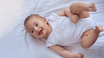 Newborn, baby and face in bed with relax for wellness, healthy development and morning routine in home. Child, happy infant and top view in bedroom with resting, wake up and comfortable in nursery