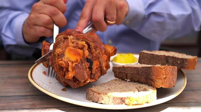 Man eating Schweinehaxe (German Pork Knuckle) or Stinco at beer hall in Germany
