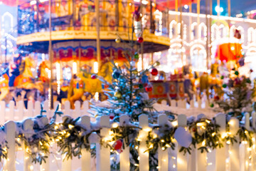 Defocused colorful merry-go-round on Christmas Fair in winter with lots of lights and bokeh on snowy evening