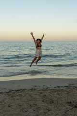 Joyful Leap: Portrait of a Woman Mid-Jump on a Sunny Beach