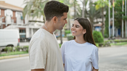 Obraz premium Smiling woman and man in casual clothes standing close in an urban outdoor setting, conveying love and togetherness