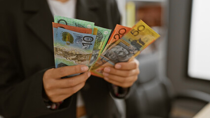 A professional woman holds australian currency in a modern office, depicting finance and workplace...