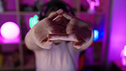 A young hispanic woman frames her face with her hands in a dark, neon-lit gaming room at night.