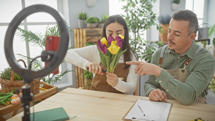 Man and woman arranging tulips for a floral tutorial in an indoor garden setting, capturing the...