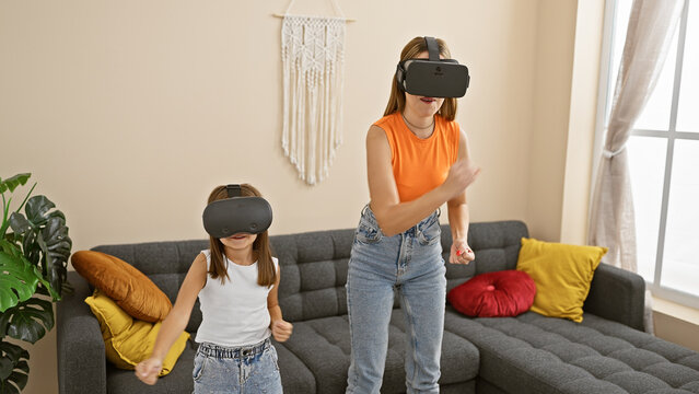 Mother and daughter play with virtual reality headsets in a cozy living room, enjoying modern family entertainment.