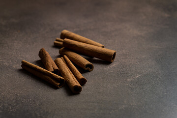 Cinnamon sticks lie on a dark gray background