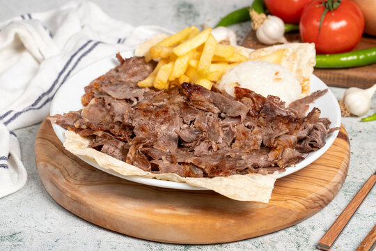 Meat doner with rice and French fries. Traditional Turkish cuisine taste. Meat doner kebab over rice cooked on a gray background. local name pilavustu et doner. Close up