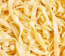 Close-up view of uncooked tagliatelle pasta creating a textured background.