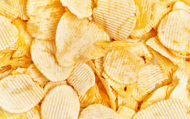 Close-up texture of crisp golden potato chips filling the entire frame, implying a snack or junk food theme.