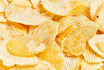 Close-up texture of crispy golden potato chips filling the frame as a background or food concept.